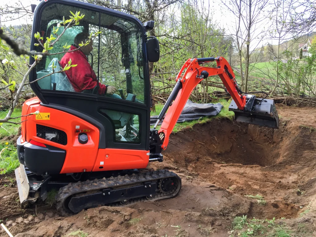 Small excavator at work making garden pond - Grass Roots Pond And Garden Small excavator at work making garden pond