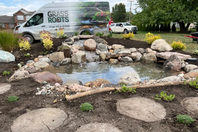 A-Grass-Roots-vehicle-next-to-a-pond-installation - Grass Roots Pond And Garden A backyard pond installed by Grass Roots with their vehicle next to it