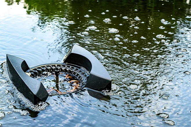 A floating pond skimmer collecting debris and leaves in a backyard pond